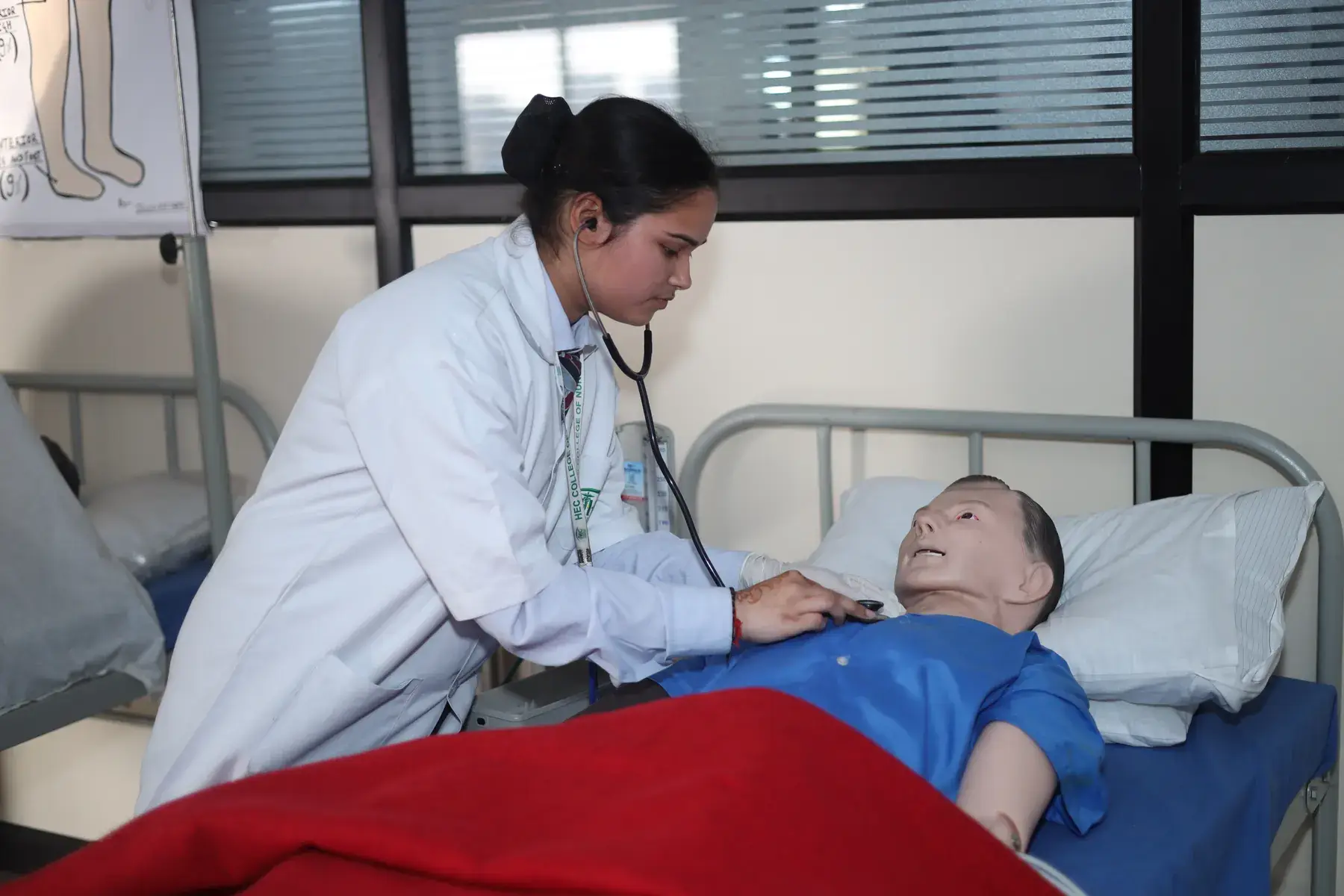 A nursing student checking a patient simulator with a stethoscope