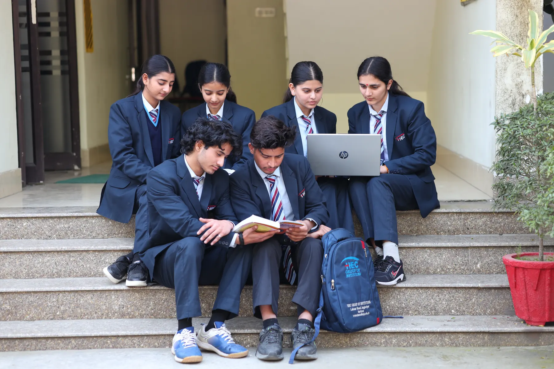 Students sharing a laptop and notes on the library steps