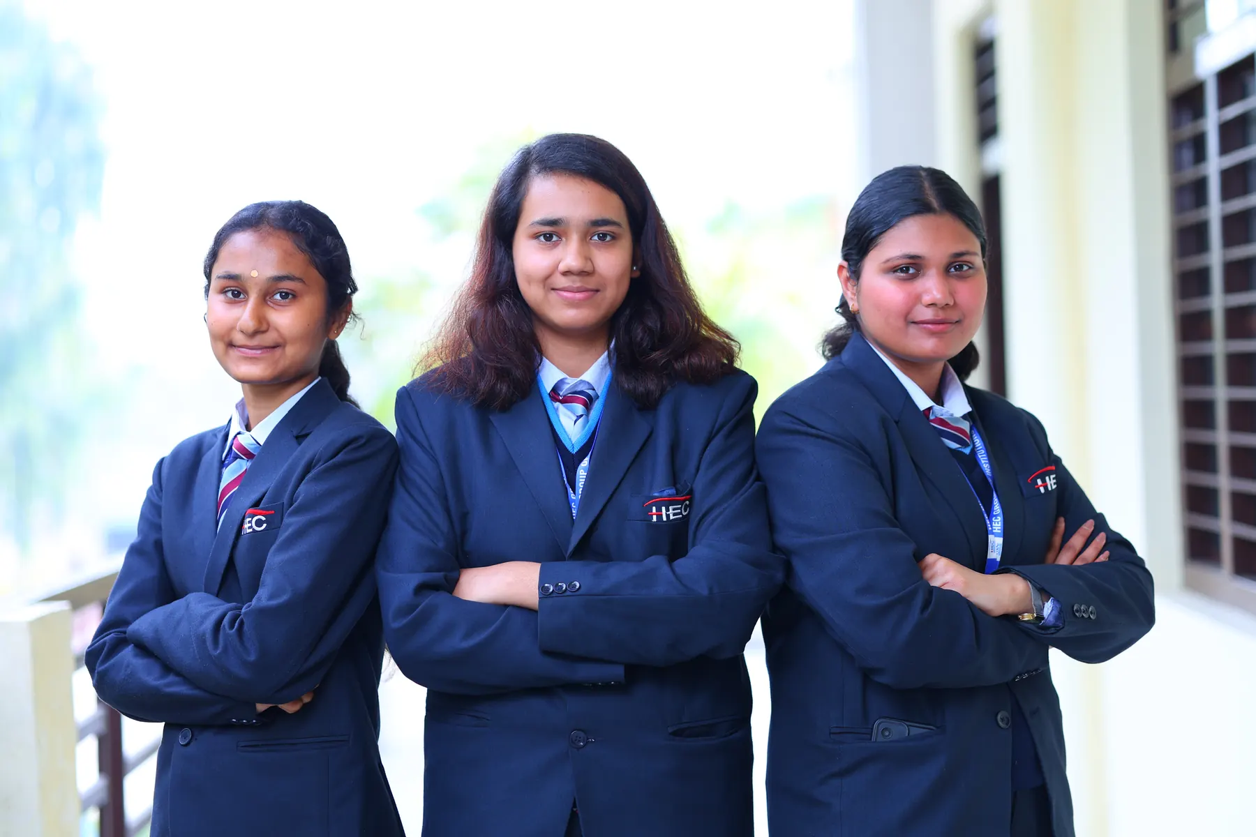 Three students in HEC blazers with arms crossed